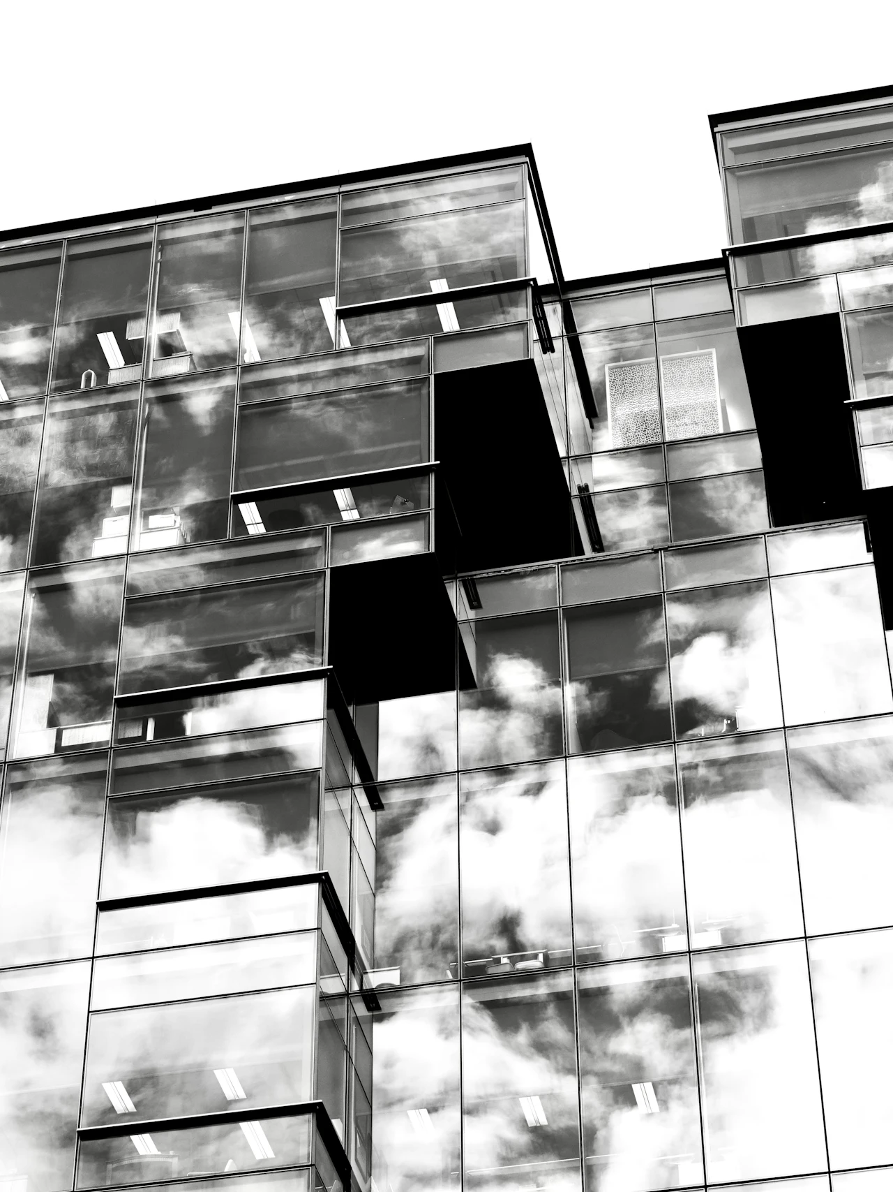 Black-and-white facade of a glass building reflecting clouds
