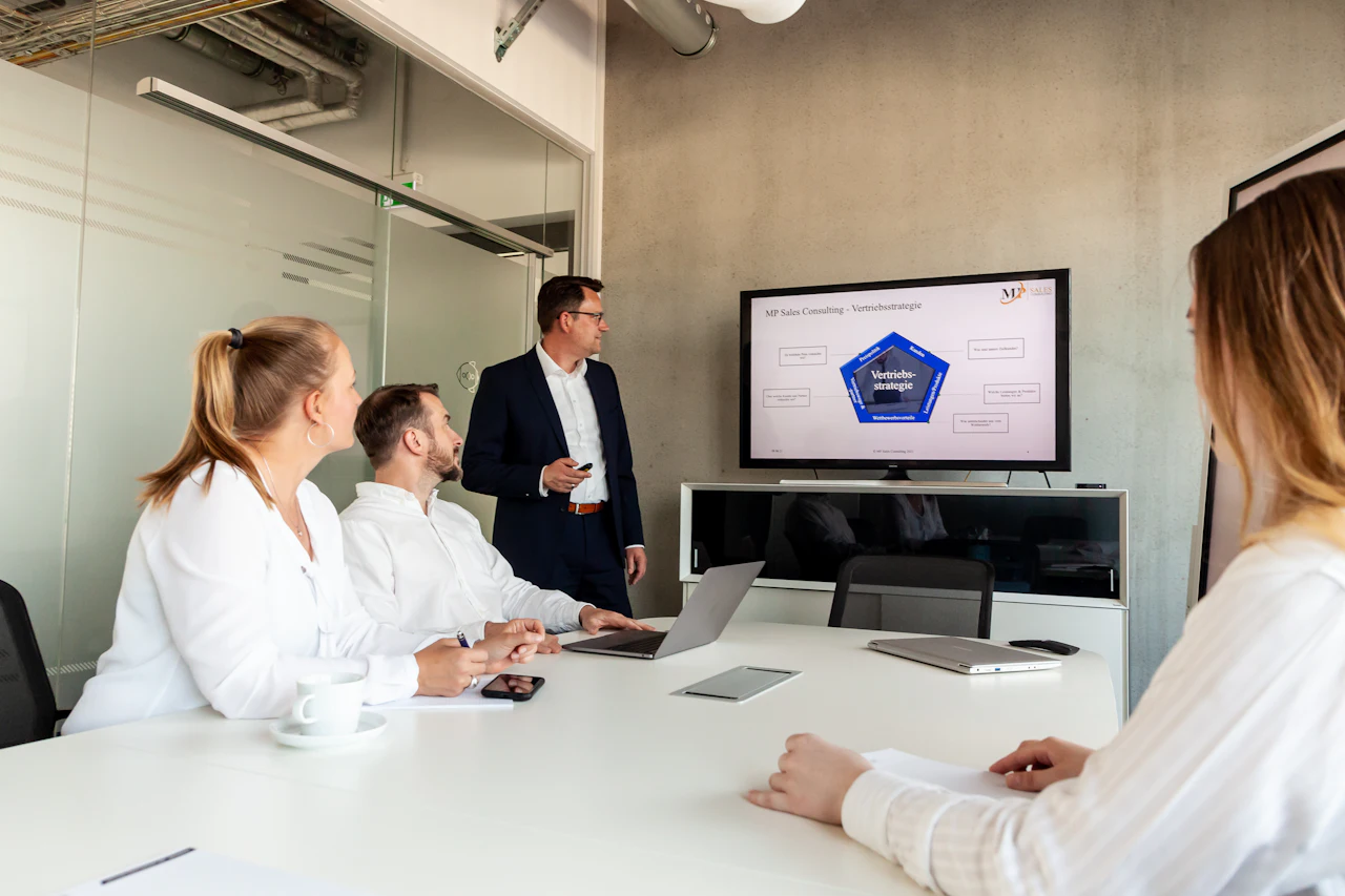 A presenter leading a meeting with colleagues around a table