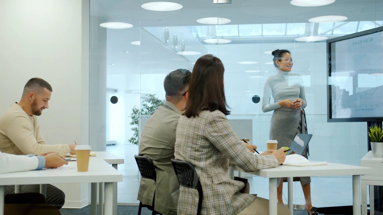 An executive presenting insights on a digital display to her team
